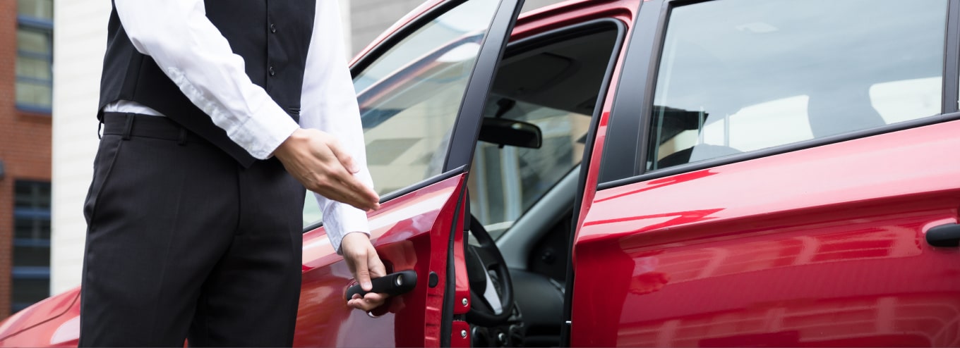 Valet opening the door of a red car