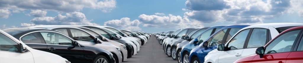 Cars parked at an angle in an outside lot with a cloudy sky